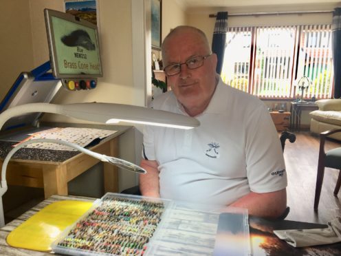 Del Tulloch, 75, of Inverness, with some of his flies; Del pictured with his CCTV and specialist lighting from Scottish War Blinded that he is using to practise tying flies again and read his fishing magazines.​