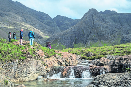 Black Cuillin and tourists visiting the Fairy Pools, succession of waterfalls in Glen Brittle on the Isle of Skye, Scottish Highlands, Scotland, United Kingdom. (Photo by: ARTERRA/UIG via Getty Images)