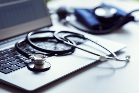 Stethoscope on laptop keyboard in doctor surgery with blood pressure monitor