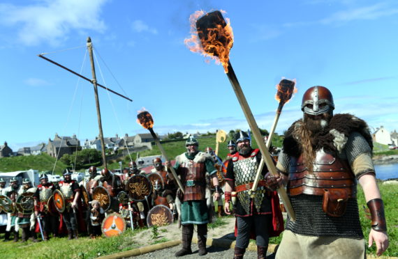 L-R Guizer Jarl's, Keith Poleson, Neil Pearson and Lyall Gair holding torches in front of their squad.   
    
Picture by Kami Thomson