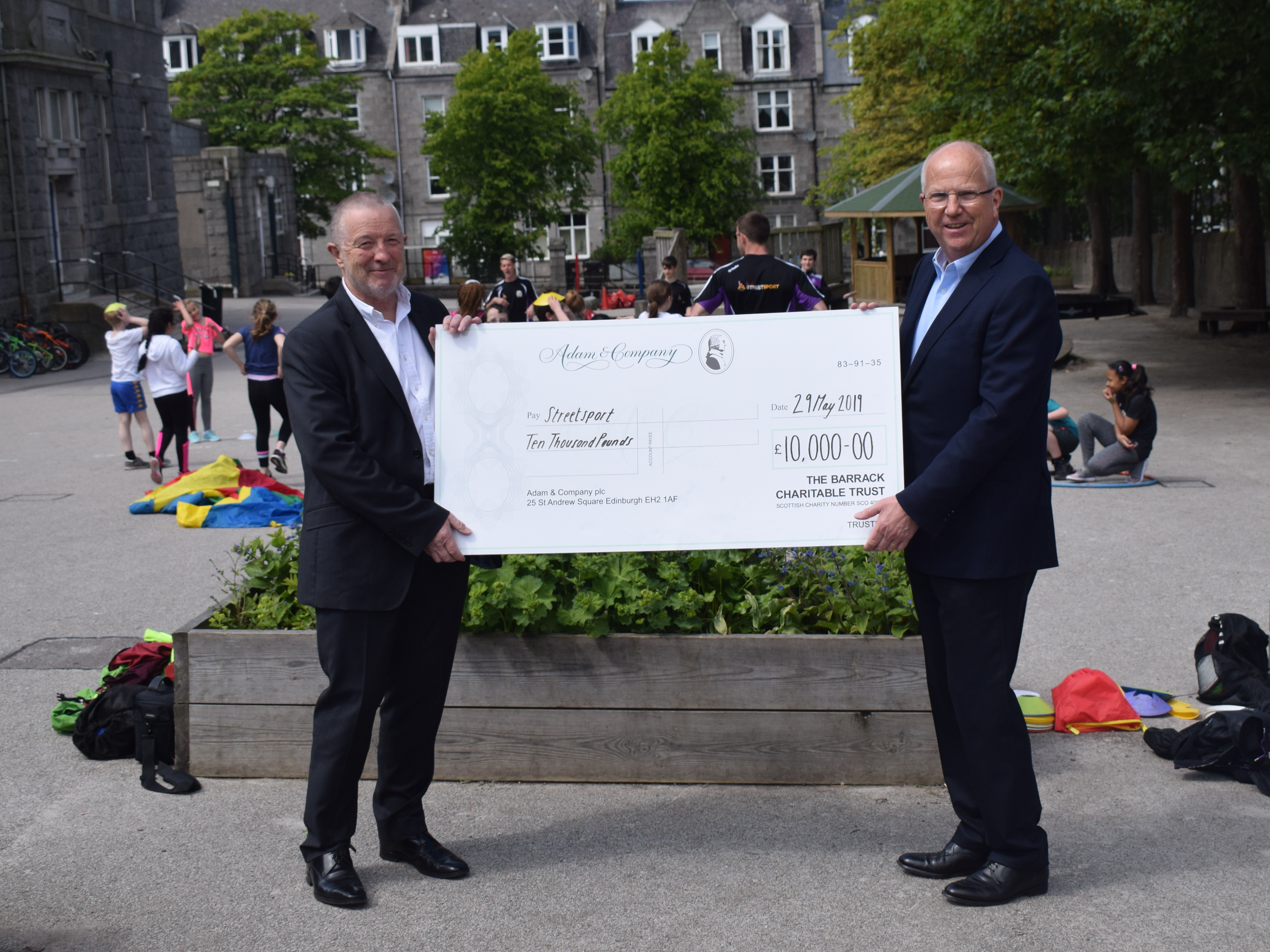 Bobby Anderson (Left) presenting chairman Graham Thom (Right) with cheque at Walker Road Primary school in Torry.