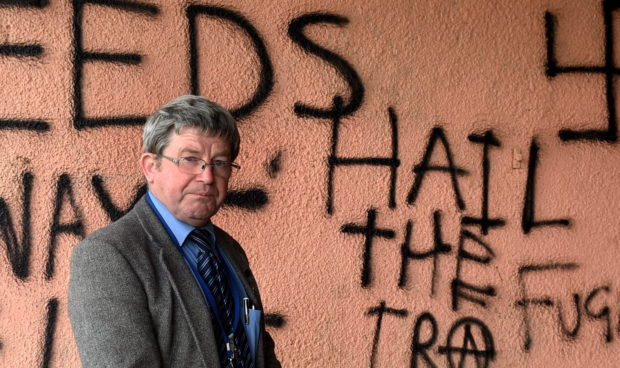 Councillor Iain Taylor highlighting the issue of vandalism as swastikas and pro IRA graffiti has been sprayed onto a wall in the Haughs, Turriff
