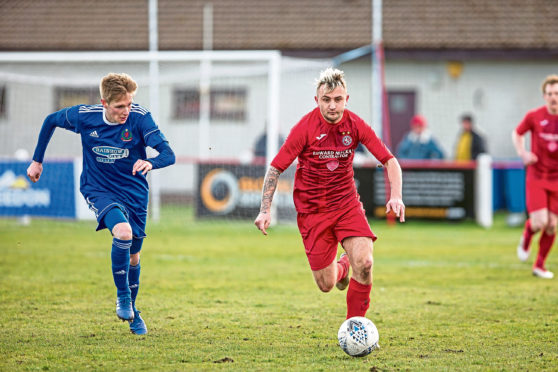 Brora's Paul Brindle breaks from Cove's Mitchel Megginson.