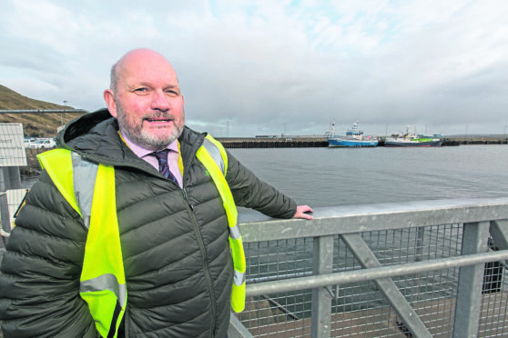 Scrabster Harbour manager Sandy Mackie with the port's St Ola Pier which is to be developed, in the background. Photo: Robert MacDonald/Northern Studios