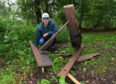 Eric Marriott is pictured in the forest area with a broken bench.