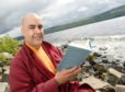 Author Gelong Thubten with his new memoir A Monk’s Guide to Happiness on the shores of Loch Ness.