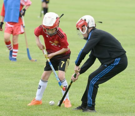 Youngsters battle over the ball during this Shinty exhibition. Picture by Sandy McCook