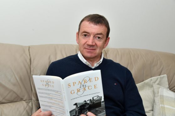 JOHN BUCHAN WITH HIS BOOK DETAILING THE HORRIFIC INJURIES HE RECEIVED IN A CAR CRASH IN 2014.