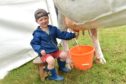 Harry Scott, 3 tries his hand at milking.
Picture by Colin Rennie
