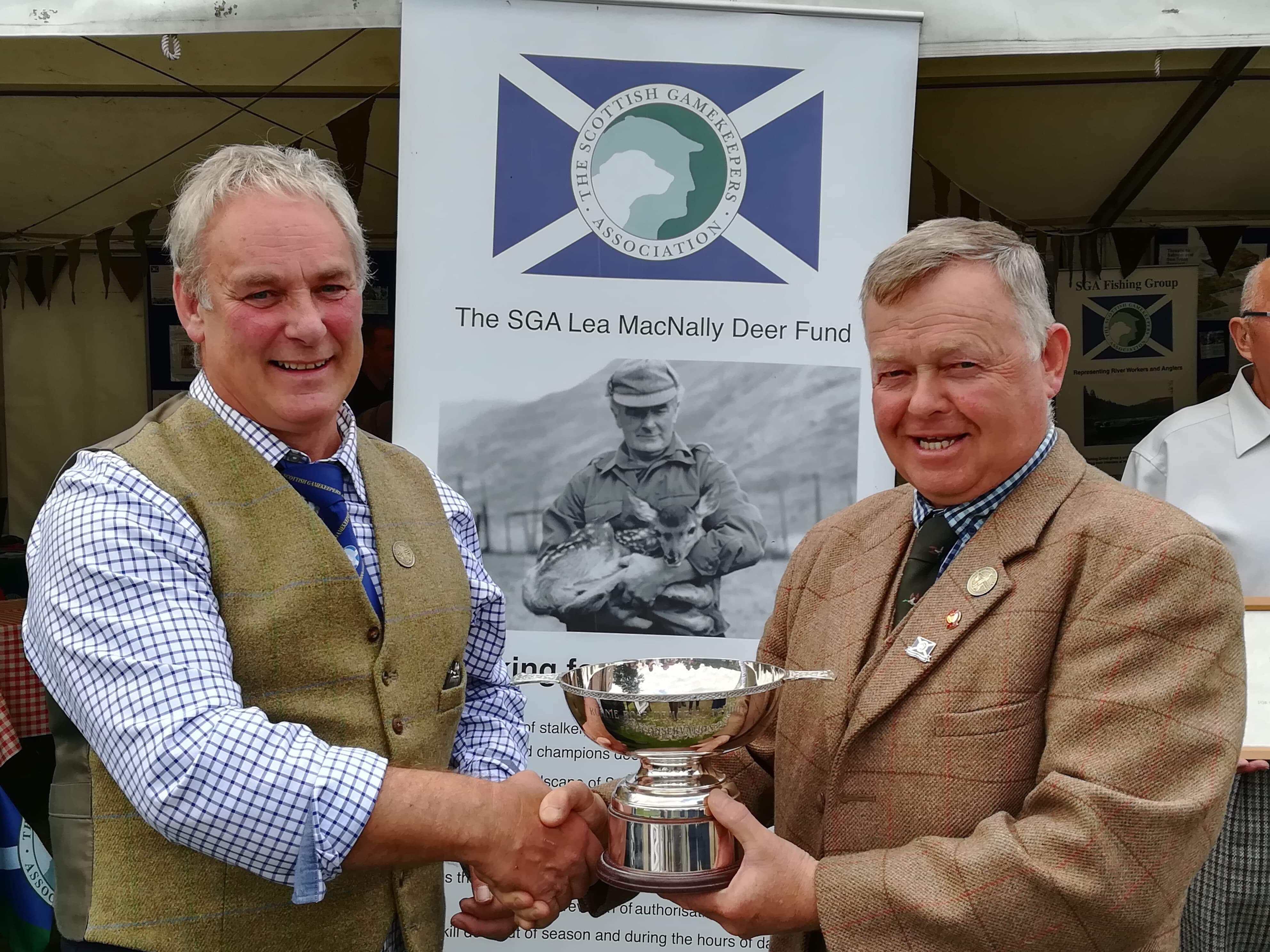 Scottish Gamekeepers Association Chairman Alex Hogg (left) presents the Ronnie Rose award to Brian Lyall at Moy Highland Field Sports Fair.