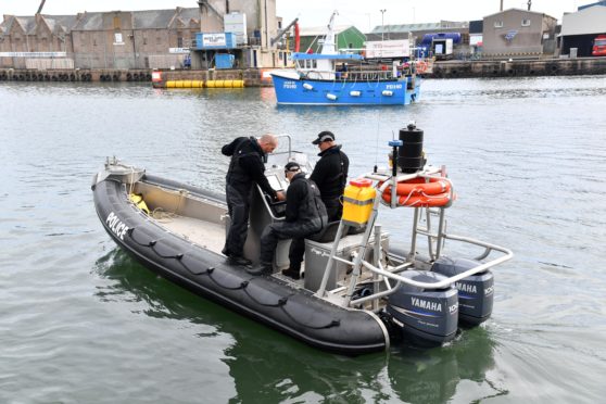 Police divers at Peterhead harbour searching with specialised sonar equipment.