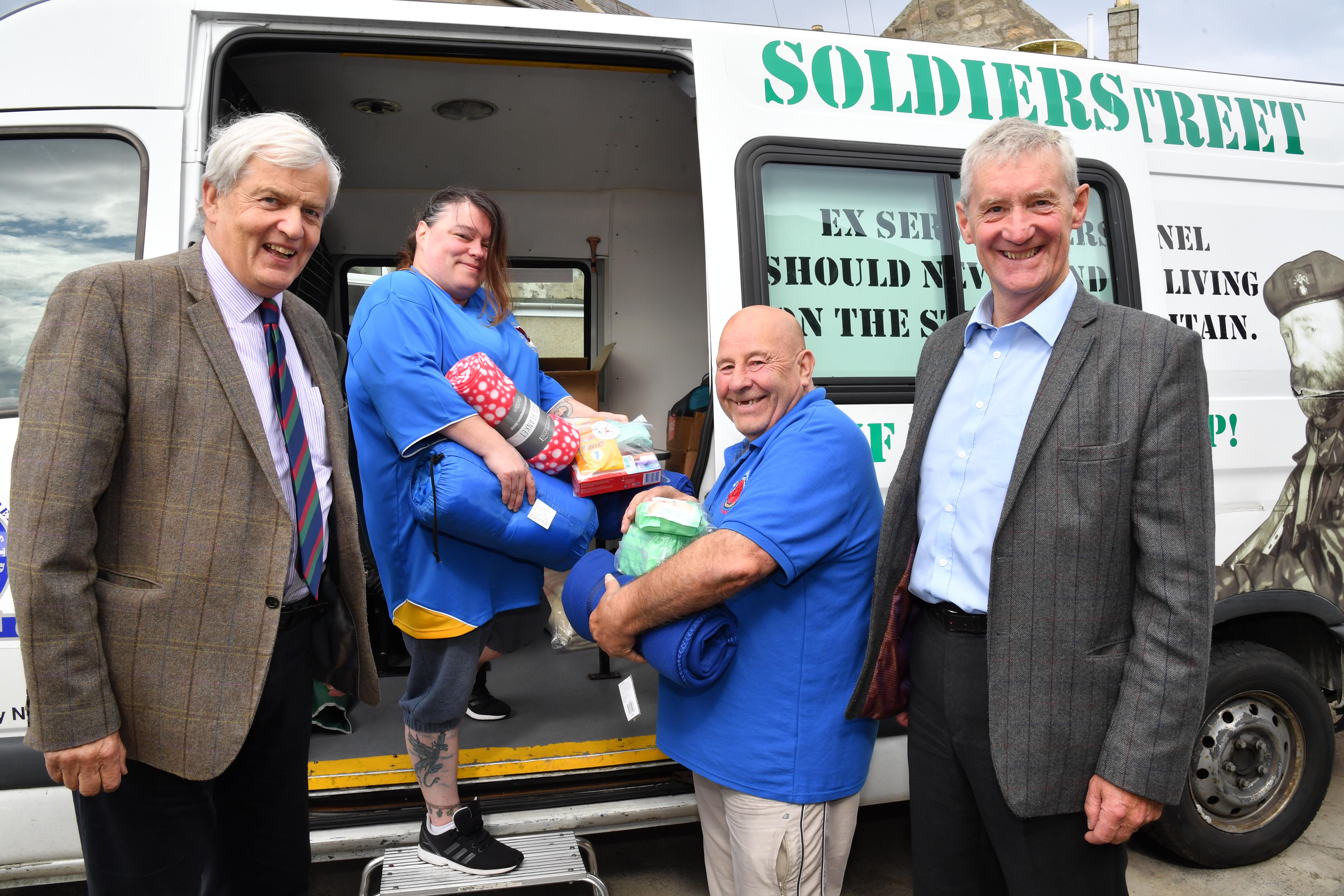 MSPs Maurice Corry (l) and Peter Chapman watch Privates on Parade volunteers Elaine Mitchell and James Grieve loading sleeping bags, blankets and hygiene kits destined for homeless veterans.