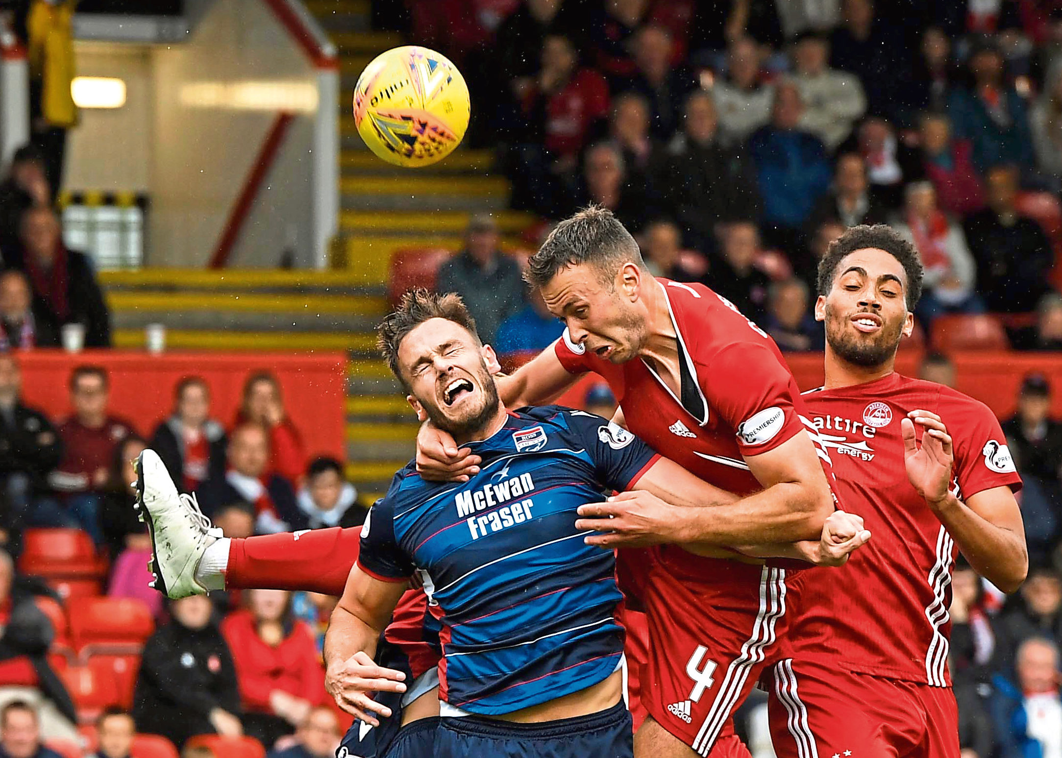 Aberdeen's Andrew Considine (C) competes with Keith Watson for the ball during the Ladbrokes Premiership match between Aberdeen and Ross County at Pittodrie Stadium on August 31