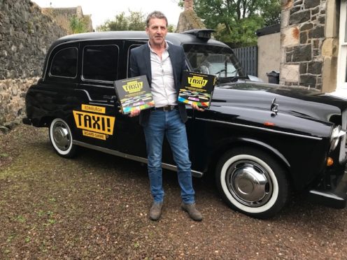 Derek Caroll holding the original Taxi board game.