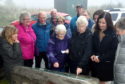 Liz Allen, centre, shows off the plaque to Cove residents.