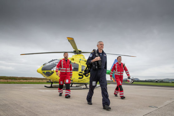 Pilot Shaun Rose and paramedics Darren O'Brien (L) and Matt Allen alongside the SCAA Helicopter