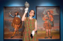 William Grant Foundation Research Fellow Dr Rosie Waine, one of the curators of the exhibition Wild and Majestic: Romantic Visions of Scotland, holds a sword which belonged to Bonnie Prince Charlie in front of a pair of portraits depicting two members of the household of the Chief of Clan Grant (paintings by Richard Waitt, 1714).