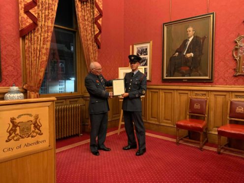 Group Captain Phil Dacre awarding Cadet Warrant Officer Jamal Ronald with the commemorative certificate