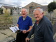 Hugh Youngson, 88, and Charlie Anderson ,91, who grandfathers built the hall, getting a preview of the book in front of the site of the former Marnoch Memorial Hall
