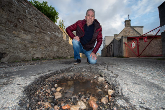 Councillor Gordon Cowie on Harbour House Lane in Buckie where the pot holes have developed over time.