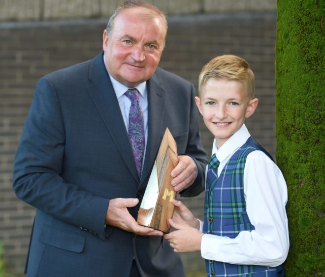 Luke Johnsson of the Sir E Scott School, Tarbert, Harris with the Tom and Rae Mitchell Memorial Trophy for traditional singing in the under 13 category. Also in the photograph is Tom Mitchell who presented the trophy in memory of his parents. Picture by Sandy McCook.
