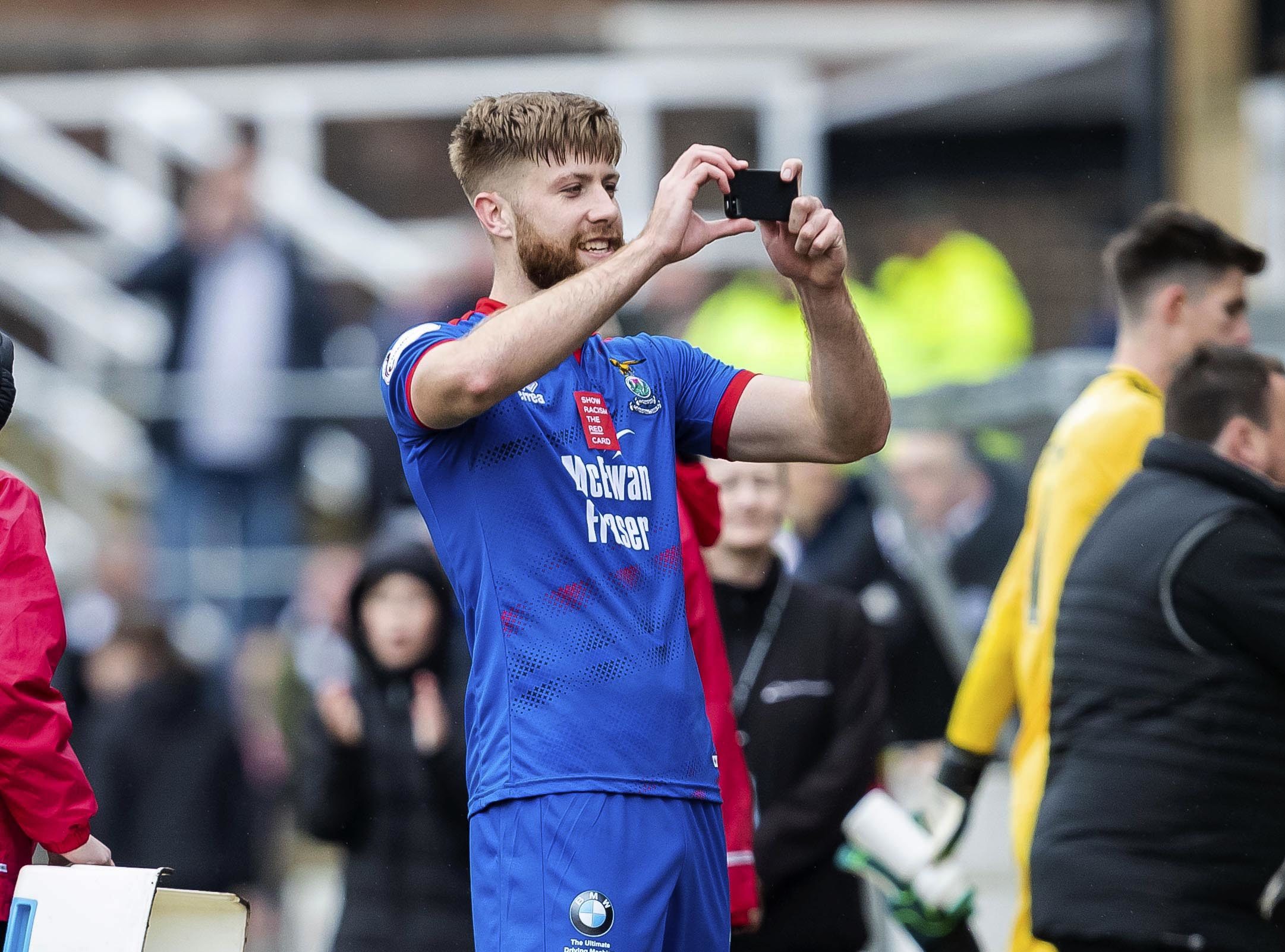 Shaun Rooney takes photos with the Caley Thistle fans at full-time.