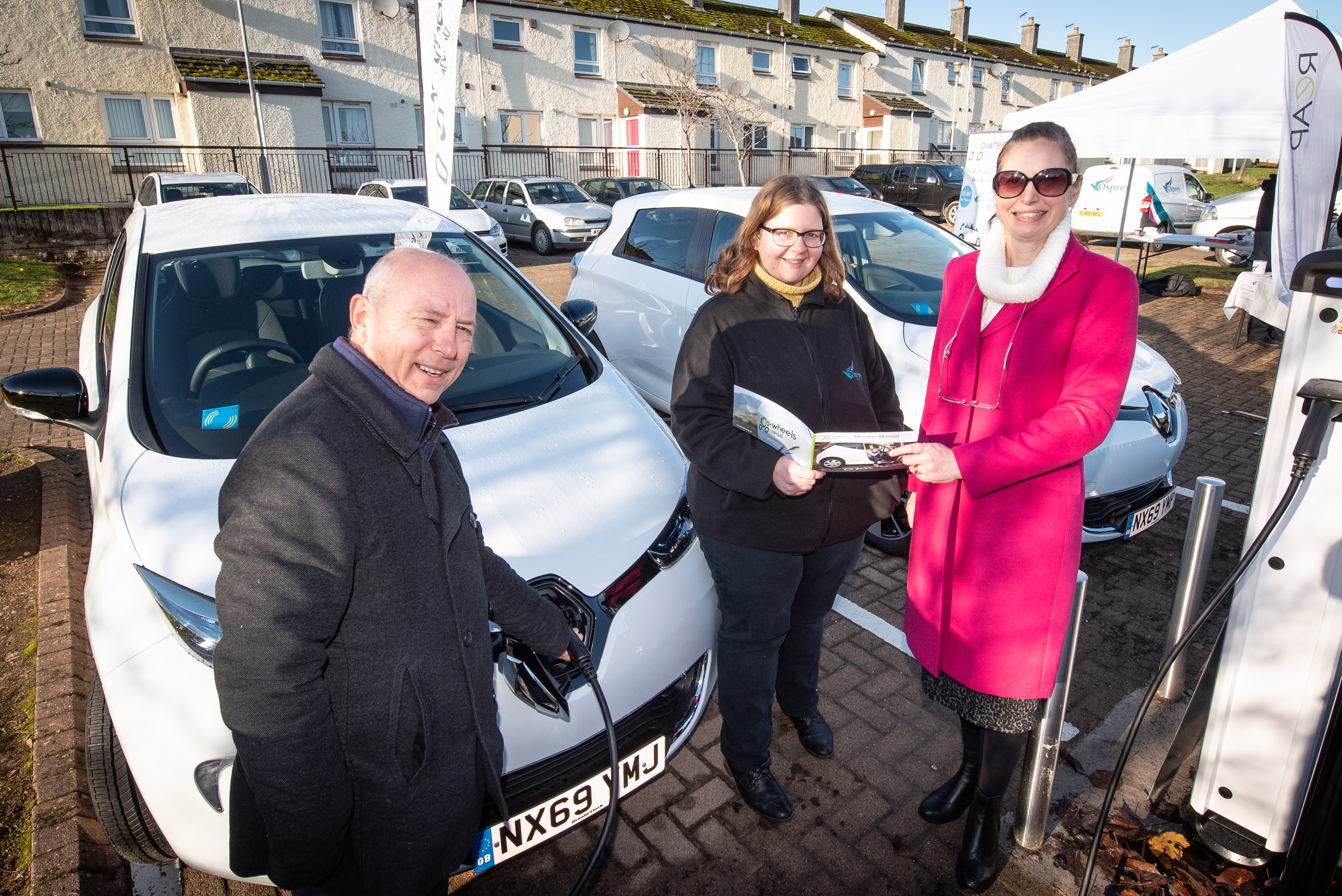 Jane McWhirr, pictured centre, Osprey Housing Group’s Sustainability Officer shows Osprey tenants David and Melanie Smith how the car club membership works.