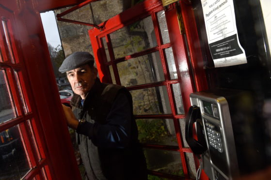 Peter Small, owner of the Tomich Hotel in the adjacent red telephone box, targeted for closure in 2019. Picture by Sandy McCook.