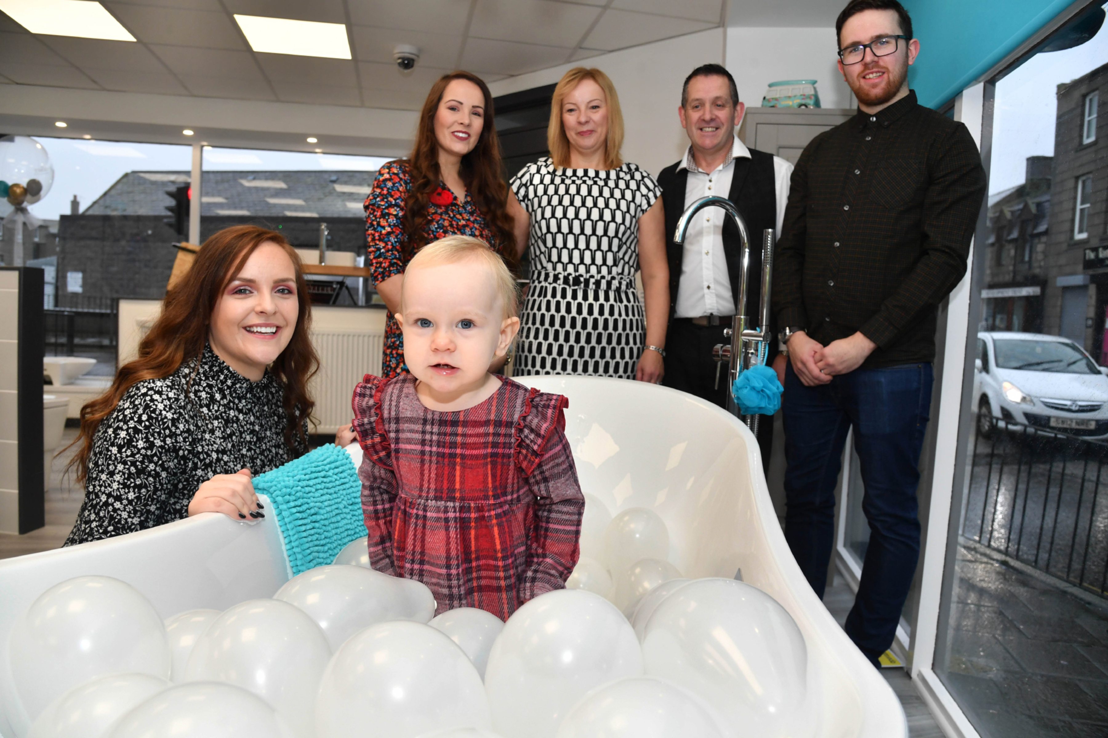 LITTLE CHARLOTTE BUCHAN CAME ALONG TO PERFORM AT THE OPENING OF HER GRANDAD BILLY WALKER'S NEW KITCHEN AND BATHROOM CENTRE IN FRASERBURGH BUT FOUND THE BUBBLE BATH MUCH MORE INTERESTING.LOOKING ON ARE (L TO R ) MUM LISA,AUNTIE EMMA HAY,LINDA AND BILLY WALKER AND DAD STUART BUCHAN.