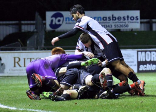 Elgin's final goalscorer Daniel McKay is buried below most of his team-mates celebrating his goal.