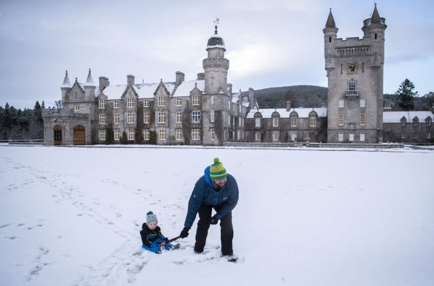 Geraint Stone pulls his two-year-old son Arthur on his sledge across the snow-covered lawn in front of Balmoral Castle, Royal Deeside.