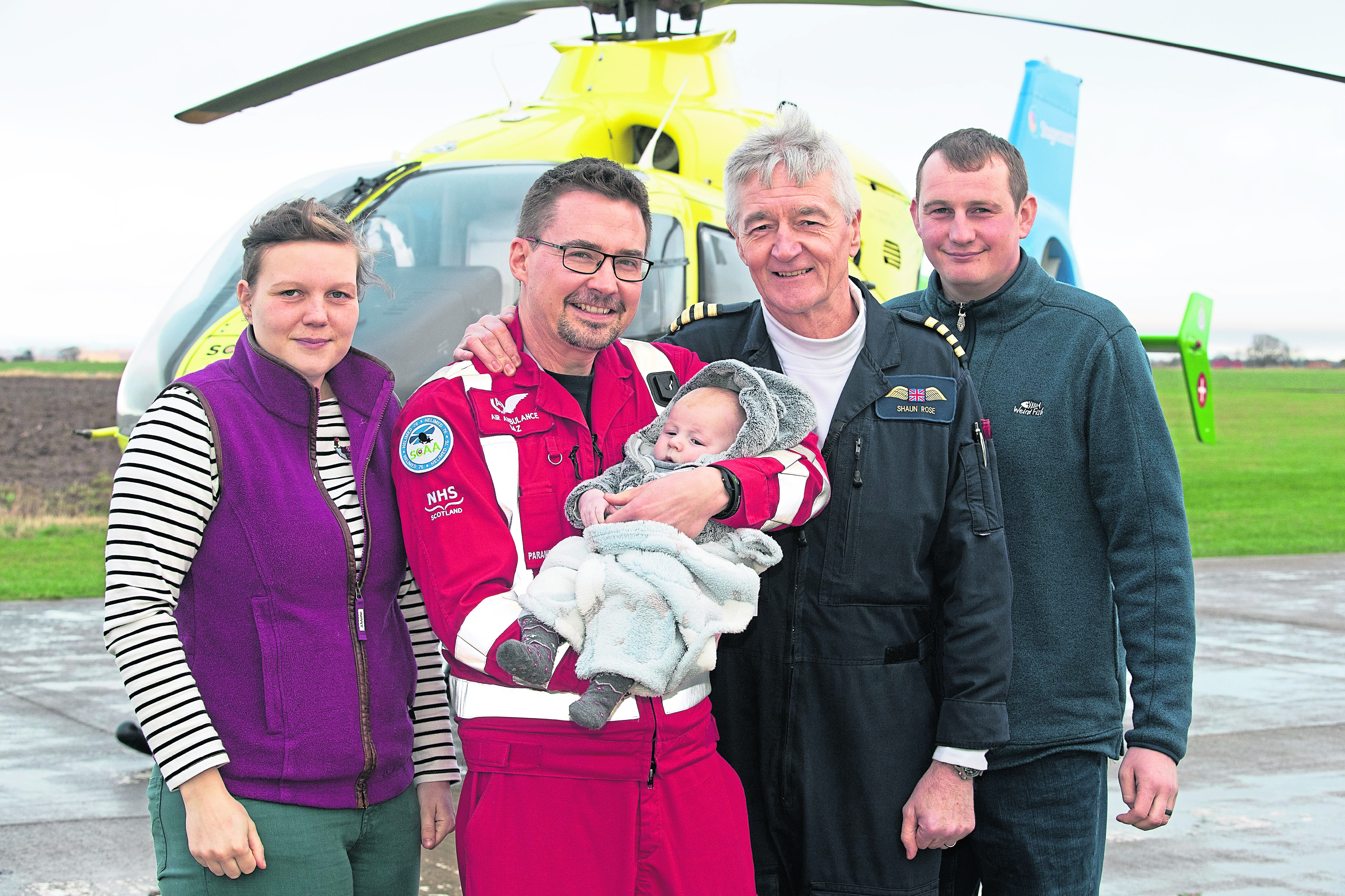 Three-month-old baby James Davidson from Glen Esk in Angus who had been savaged by a family dog pictured on a visit to Scotland's Charity Air Ambulance to say thank you to the crew who helped to save his life. Pictured from left, Morven Davidson (Mum), Paramedic Darren O'Brien holding baby James, Pilot Captain Shaun Rose and Derek Davidson (Dad).
Picture by Graeme Hart