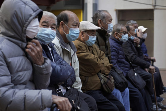 Elderly men sit at a park wearing face masks in Hong Kong, Thursday, Jan. 30, 2020. Hong Kong cut off rail service to mainland China at midnight on Wednesday to Thursday to try to stop the spread of the coronavirus to the city.