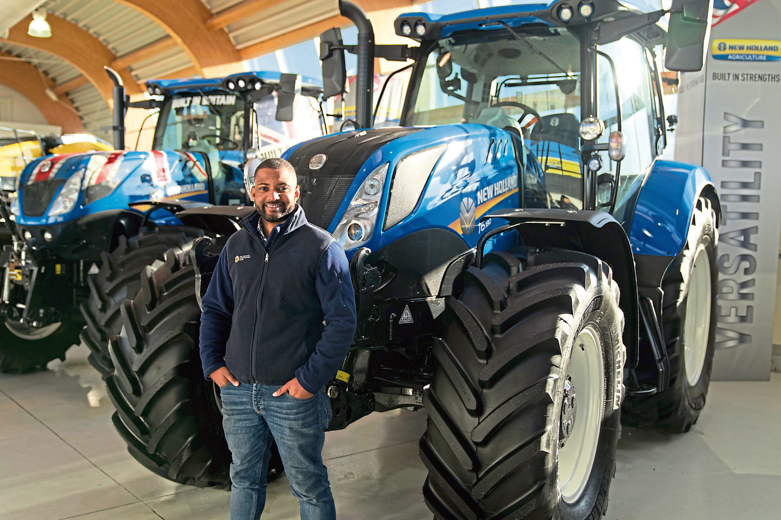 JB Gill beside a line-up of New Holland machinery.