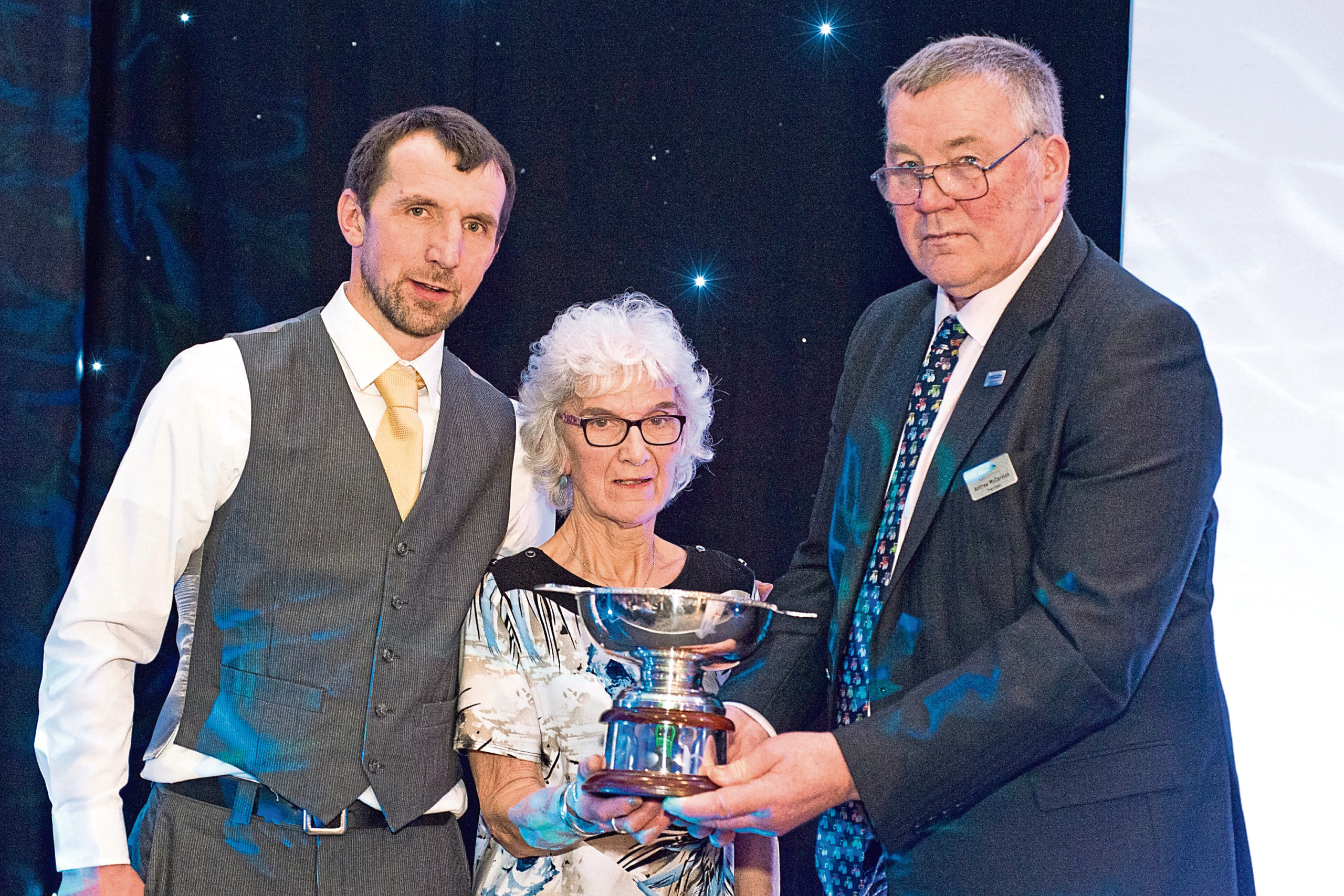 Jan Innes and son James collect the award from NFU Scotland president, Andrew McCornick, on the right.