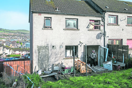 Police maintain a presence at  a house in Dingwall where a suspected small explosion took place hospitalising two.