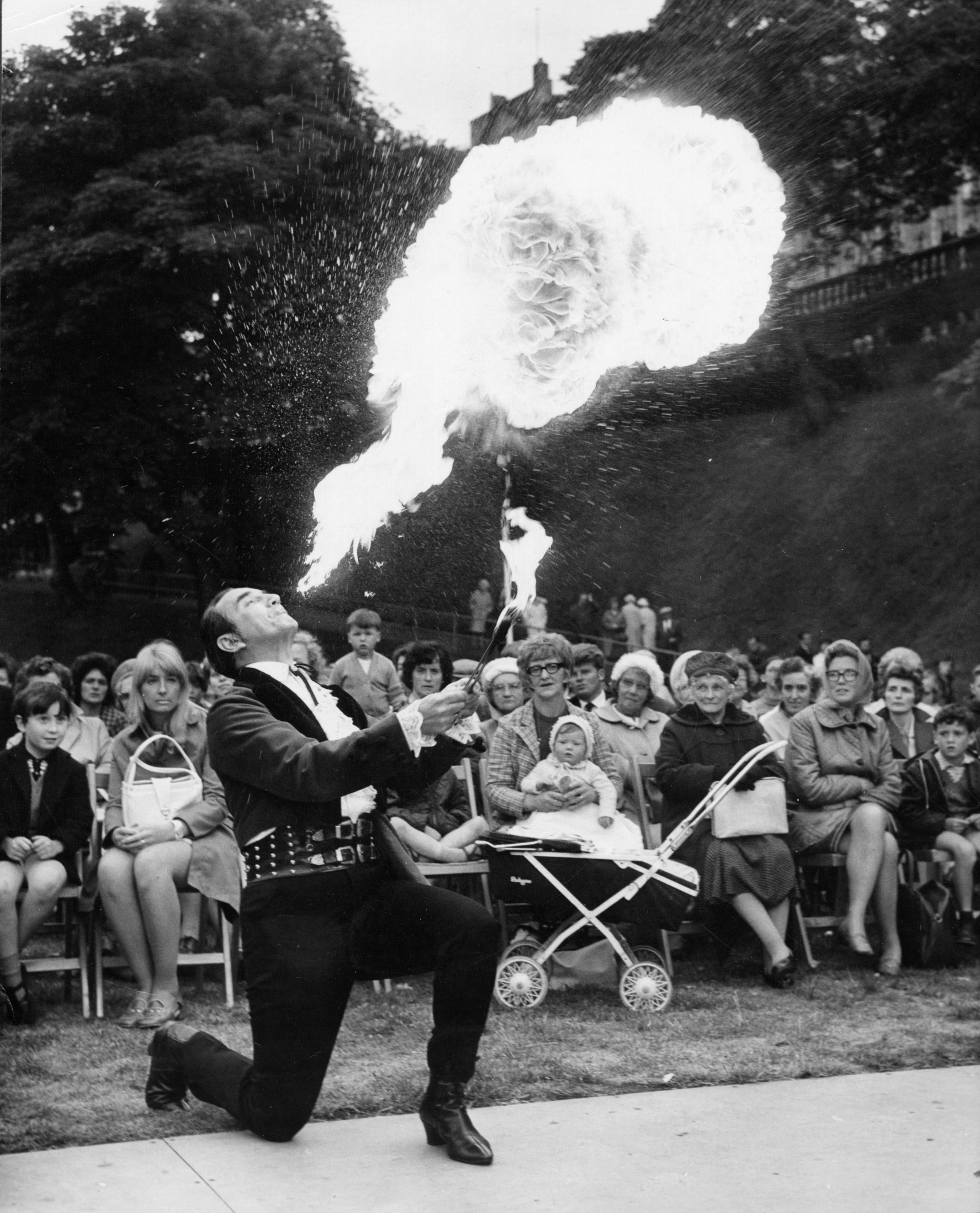 A fire-eater with a seated crowd watching.