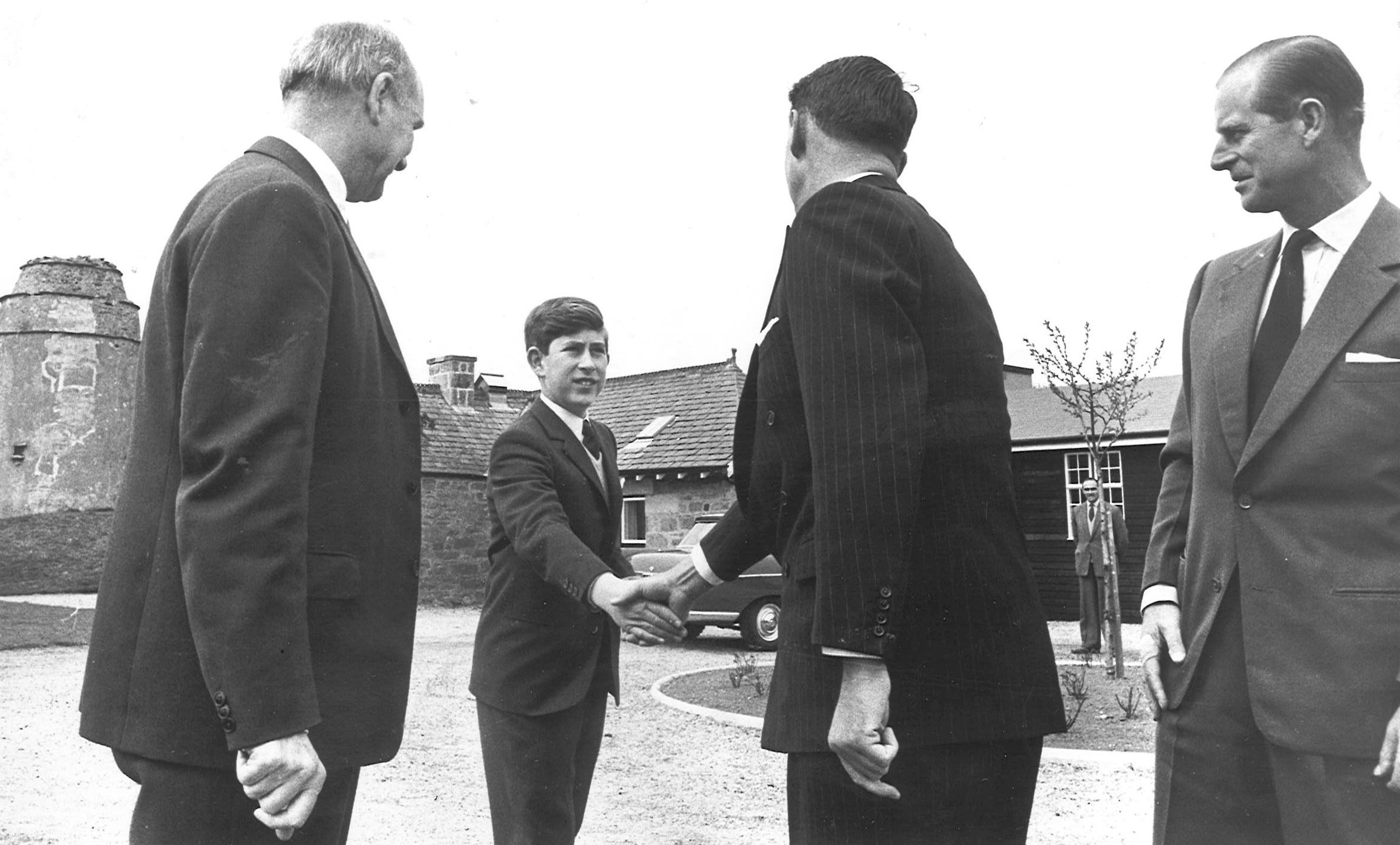 Prince Charles shakes hands with his housemaster Robert Whitby, looking on is the Duke and Gordonstoun headmaster Robert Chew.