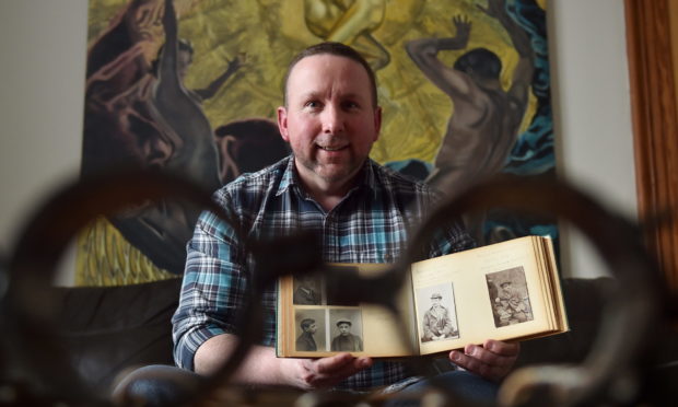 Craig Pithie with his book of mugshots. Photo by Scott Baxter.