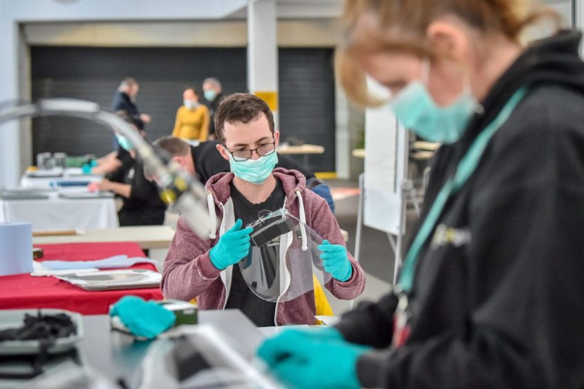 Royal Mint employees assemble full face visors in the cafe inside the Royal Mint Experience.