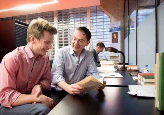 The authors, at work in the University Library of Leiden, Dr Arthur der Weduwen (left) with Professor Andrew Pettegree, holding the first book ever to be advertised in a newspaper