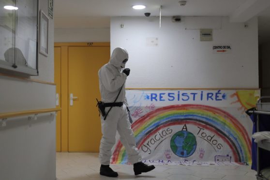 A member of the UME (Emergency Army Unit) wearing a protective suit to protect against coronavirus disinfects next to a banner reading in Spanish: "I will resist, Thanks everybody" at a nursing home in Madrid.