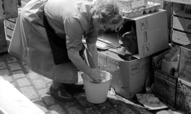 Woman washes her hands in a bucket during typhoid crisis in 1964.