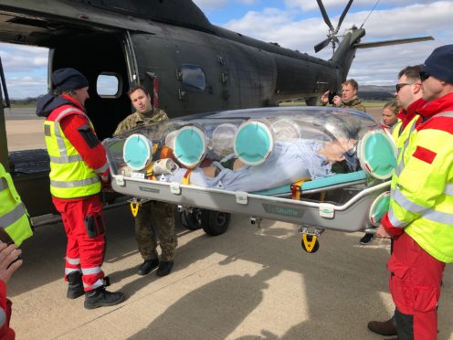 A Puma crewman supports the doctors and Paramedics of the Scottish Ambulance Service during the loading of the EpiShuttle onto the helicopter.