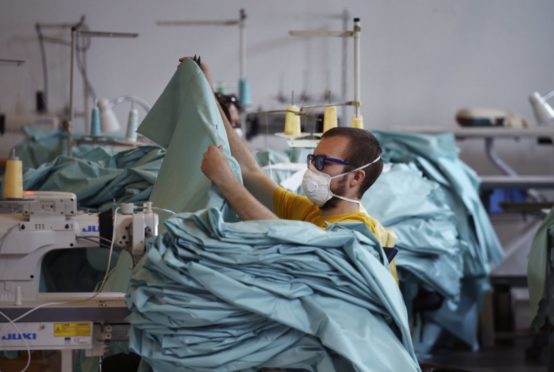 A worker quality checks a stack of PPE before the items get shipped.