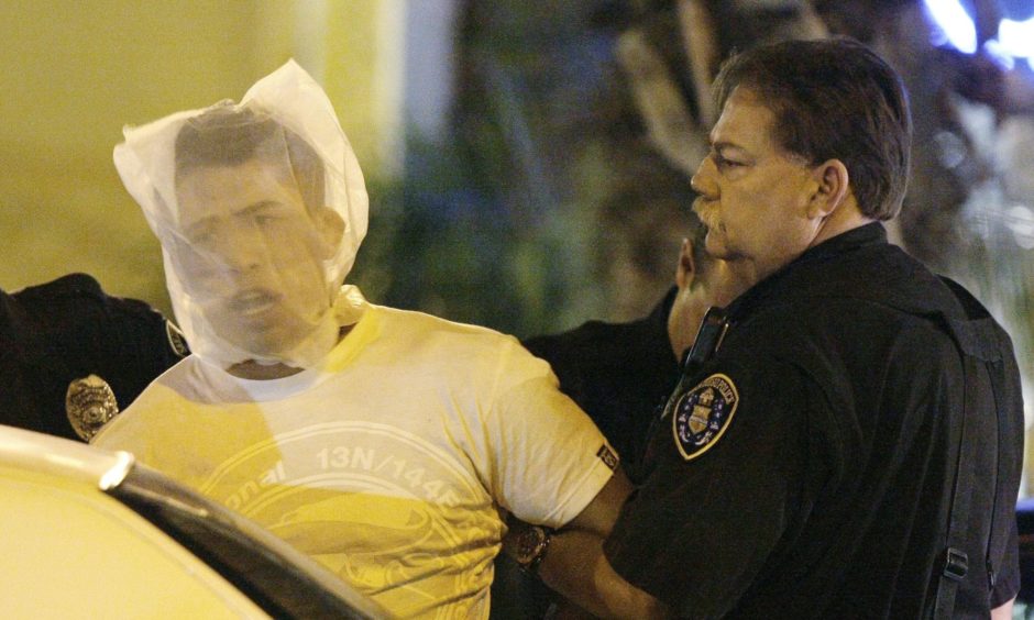 Police officers in the United States detaining a man with the help of a spit guard.
