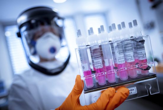 A research assistant holds coronavirus test samples in her hands