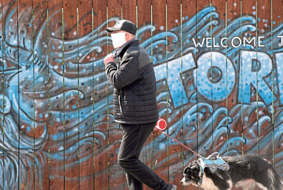 A member of the public covers his face with a mask during the Covid-19 lockdown in Torry, Aberdeen. Picture by Kath Flannery.
