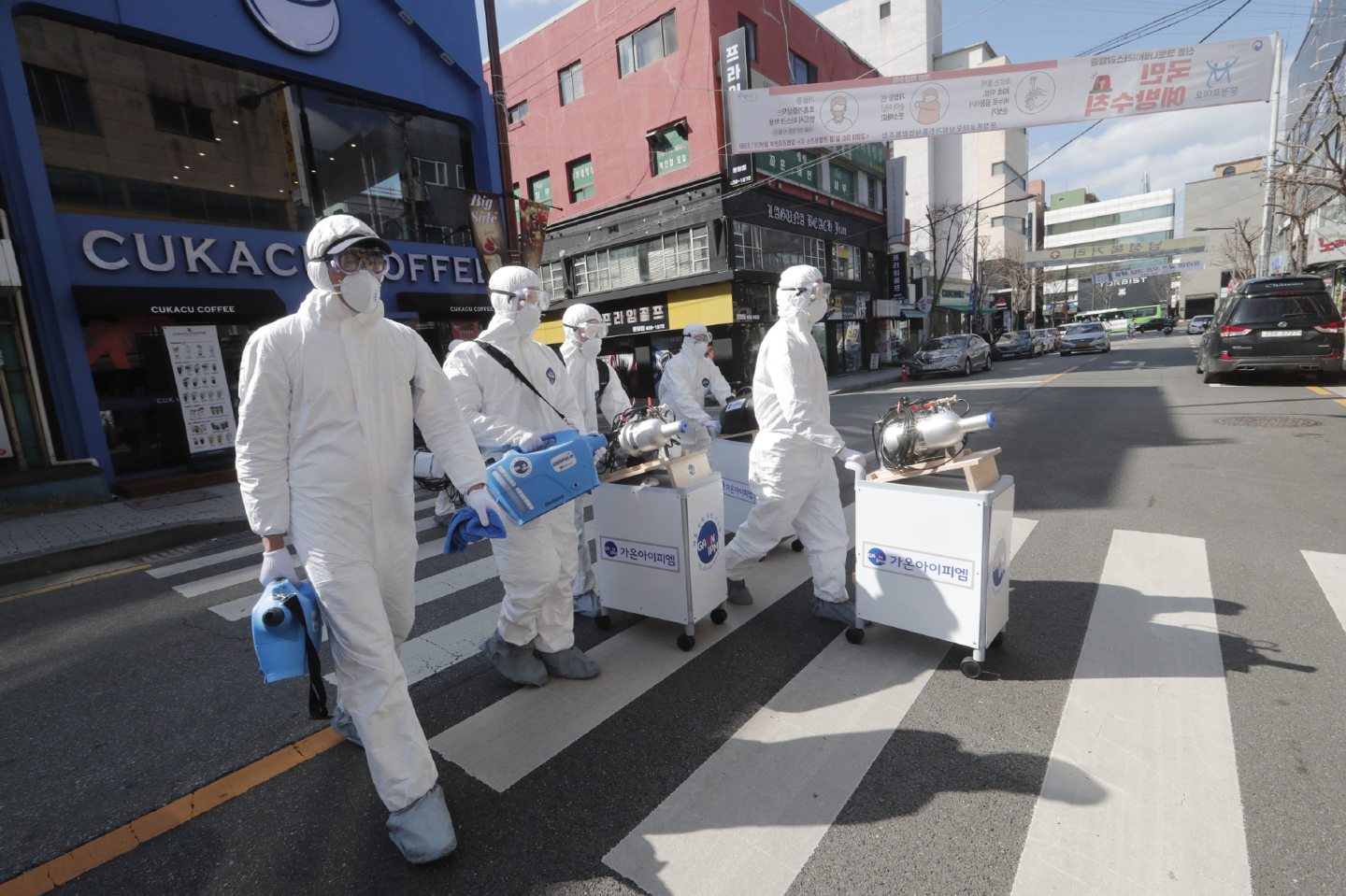 Workers wearing protective gear spray disinfectant as a precaution against the coronavirus in Seoul.
