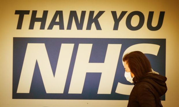 A woman walks past a sign thanking NHS workers.